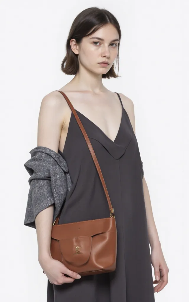 A French female model with an Unstructured bag, wearing a dress, against a white background, in a front   facing close   up